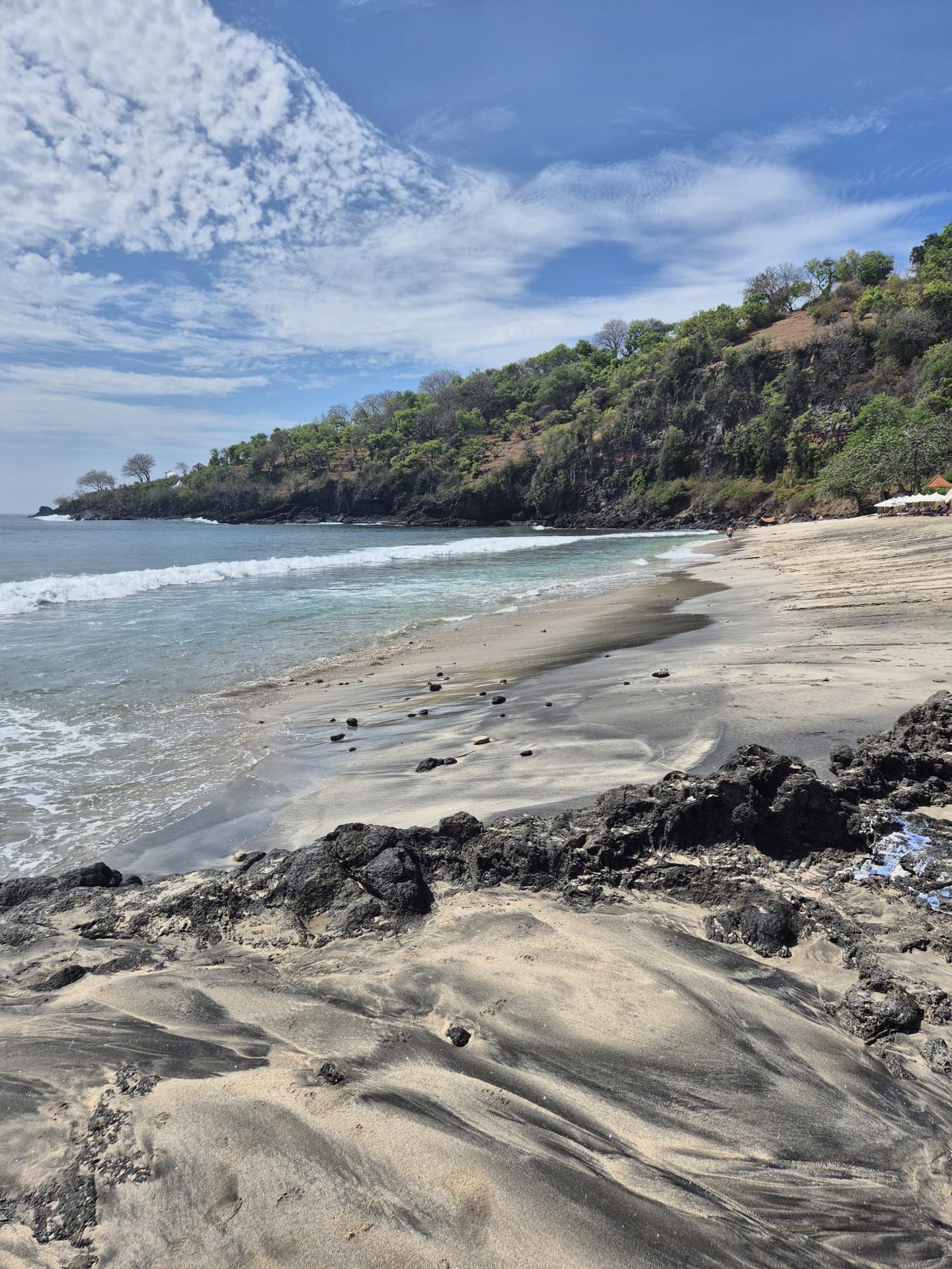 Strand mit schwarzen Lavafelsen an der Ostküste Balis